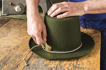 Tightening the shaping cord around a wool felt hat, using iron tool, hatmaker workshop, Bad Aussee, Styria, Austria, Europe