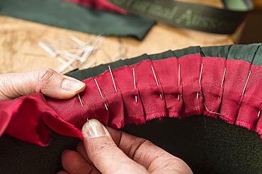 Hands folding and fastening silk ribbon using pins, inner lining of a wool felt hat, hatmaker workshop, Bad Aussee, Styria, Austria, Europe