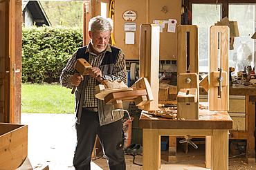 Wooden mask carver using wood carving tools at workbench in workshop, Bad Aussee, Styria, Austria, Europe