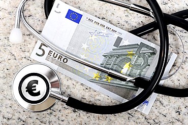 Doctor's stethoscope and a five euro banknote, symbolic image for the payment of five euro per doctor visit