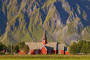 The red stave church of Flakstad in front of steep mountains, Vareid, Fredvang, island of Flakstadoya, Flakstadoya, Lofoten archipelago, Nordland, Norway, Europe