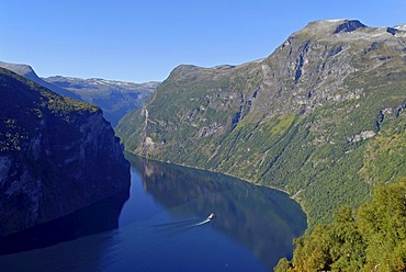 A lone boat on the calm Geirangerfjord, surrounded by steep mountains, Moere og Romsdal, Norway, Europe