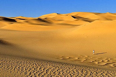 Woman walking on a sand dune near Tehenadou, Adrar n'Ahnet, Algeria, Sahara, North Africa