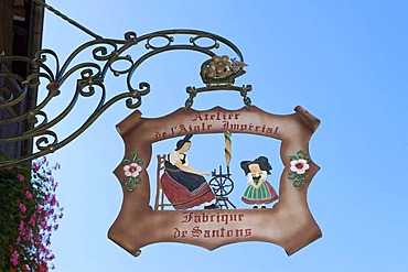 Hanging sign depicting people in typical traditional costume in Kaysersberg, Alsace, France, Europe