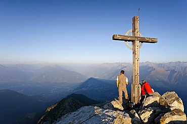 Climber at sunrise at the summit cross of Ifingers Mountain above Meran, Meran 2000, Alto Adige, Italy, Europe