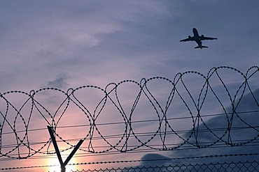 Security fence with an aircraft flying above, Stuttgart airport, Baden-Wuerttemberg, Germany, Europe