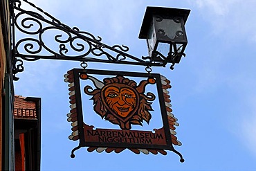 Hanging sign against a blue sky, Narrenmuseum, a museum inside Niggelturm tower, Hauptstrasse 39, Gengenbach, Baden-Wuerttemberg, Germany, Europe