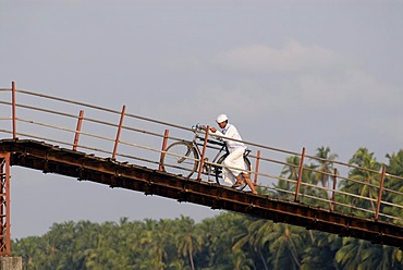 Man walking his bike on a bridge across the Backwaters, Nileshwaram, Malabar Coast, northern Kerala, Kerala, southern India, India, Asia