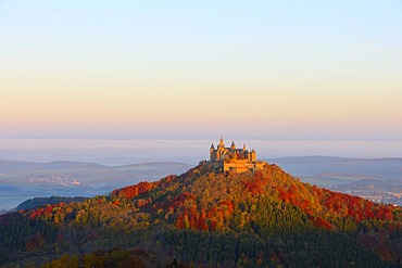 Burg Hohenzollern Castle in the early morning light with autumnal forest, early morning fog, Swabian Alb, Baden-Wuerttemberg, Germany, Europe