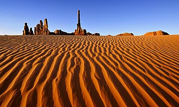 Sand dunes in front of Totem Pole and Yei Bi Chei rock formations after sunrise, Monument Valley, Navajo Tribal Park, Navajo National Reservation, Arizona, Utah, USA