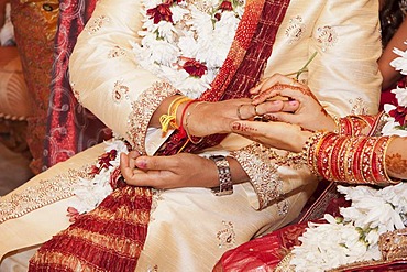 Indian bride passing wedding ring on her groom's finger