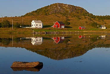 Reflections of some lonely houses in a calm fjord near Solberg, Nordland, Norway, Europe