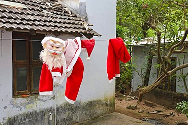 Santa Claus costume drying on a laundry line after Christmas time in Varkala, Kerala, India, Asia