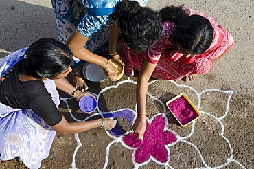 Women making Rangoli, decorative sand designs in the streets of Madurai during a Hindu festival, meant as sacred welcoming area for the deities, Tamil Nadu, India, Asia