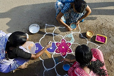 Women making Rangoli, decorative sand designs in the streets of Madurai during a Hindu festival, meant as sacred welcoming area for the deities, Tamil Nadu, India, Asia