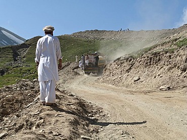 Local man watching his friends hitching a ride up to Babusar Pass, Chillas, North West Frontier, Pakistan, South Asia