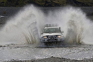 Super jeep driving through a tributary of the Krossa River, ï¬orsmoerk, Iceland, Europe