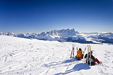 Cross-country skiers taking a break on the summit of Uribrutto Mountain above the Passo Valles, looking towards the Palla Group and the Rolle Pass, Trentino, Dolomites, Italy, Europe