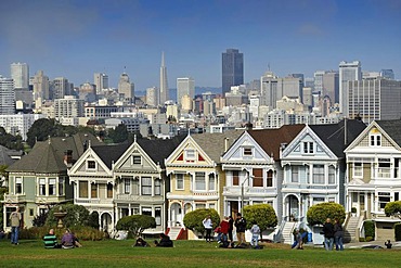 Tourists in front of Painted Ladies, Victorian, multi-coloured painted wooden houses in front of the skyline with the Transamerica Pyramid, Steiner Street, Alamo Square, San Francisco, California, United States of America, USA, PublicGround