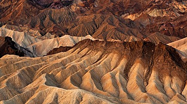 View from Zabriskie Point to Manly Beacon with its eroded rocks coloured by minerals, Panamint Range at back, dawn, sunrise, Death Valley National Park, California, USA