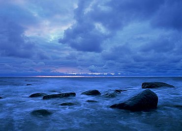 Waves washing over rocks under a cloudy sky before sunrise, Jasmund National Park, Ruegen Island, Mecklenburg-Western Pomerania, Germany, Europe