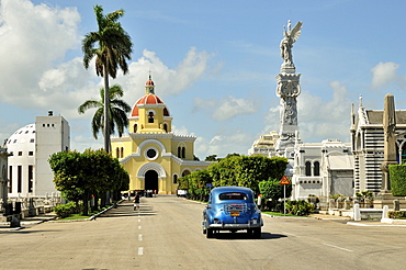 Classic car driving in front of a chapel on Colon Cemetery, Cementerio Cristobal Colon, named after Christopher Columbus, Havana, Cuba, Caribbean