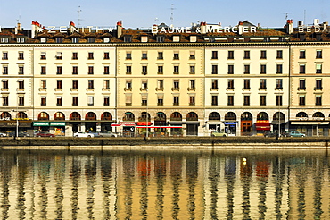 A row of houses on Quai des Bergues street is being reflected in the water of the Rhone River in downtown Geneva, Switzerland, Europe