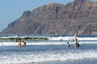 Tourists in the water, beach Playa de Famara, La Caleta de Famara, west coast of Lanzarote, Canary Islands, Spain, Europe