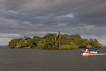 Tourist boat in front of small island with tropical vegetation in Lake Nicaragua, Isletas, Lago de Nicaragua, Nicaragua, Central America