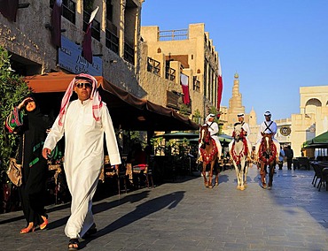 Man wearing a traditional Thobe and mounted police in front of the tower of the Islamic Cultural Centre FANAR, Souk Waqif, Doha, Qatar, Middle East