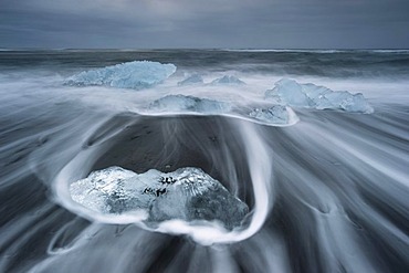 Melting icebergs lying in the strong surf on the black volcanic beach at Joekulsarlon, Iceland, Europe