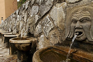 Row of fountains with stone heads spouting water in Roccalbegna, Province Grosseto, Tuscany, Italy, Europe