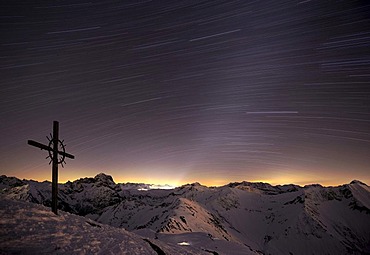 Mountain panorama with a starry sky and summit cross at the blue hour in winter, Baad, Kleinwalsertal, Vorarlberg, Austria, Europe