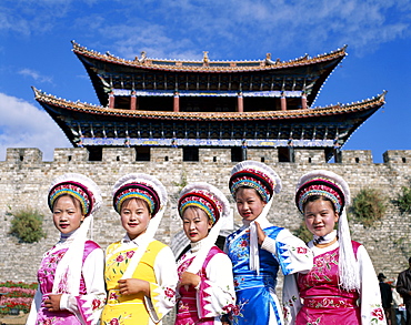 Bai Minority women dressed in Bai traditional costume in front of Town walls and Old Town Gateway, Old Town, Dali, Yunnan Province, China, Asia