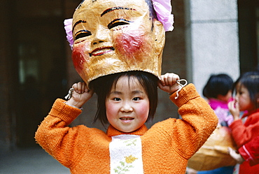 Young girl with Chinese Lucky God mask, Beijing, China, Asia