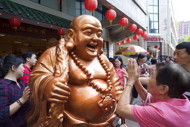 Woman praying to Buddha statue for good fortune, Chinatown, Singapore, Southeast Asia, Asia