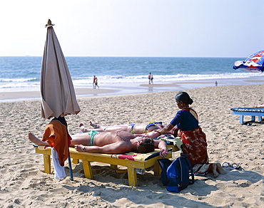 Local woman giving massage to tourist, Colva Beach, Goa, India, Asia