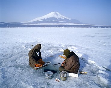 Mount Fuji and fishermen on frozen Lake Yamanaka, Honshu, Japan, Asia