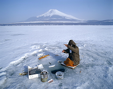 Mount Fuji and fisherman on frozen Lake Yamanaka, Honshu, Japan, Asia