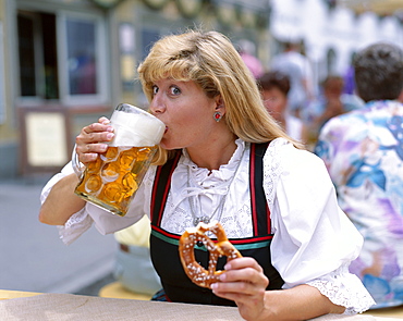 Girl in Bavarian costume drinking beer and eating pretzel, Rosenheim, Bavaria, Germany, Europe