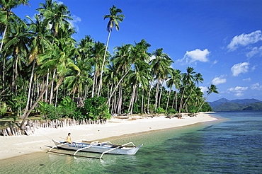 Girl sitting in outrigger on tropical beach, Bascuit Bay, El Nido, Palawan, Philippines, Southeast Asia, Asia