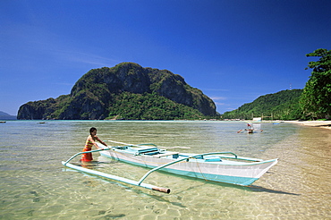 Girl with outrigger boat on tropical beach, El Nido, Bascuit Bay, Palawan, Philippines, Southeast Asia, Asia