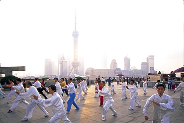 People doing tai-chi at dawn with Pudong skyline in background, Shanghai, China, Asia