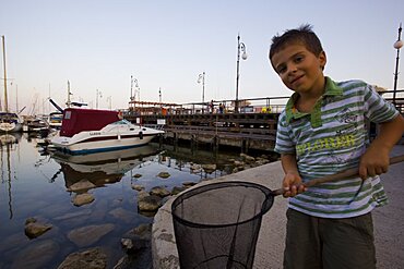 Cypriote boy fishing in a marina in Cyprus at dusk, Cyprus