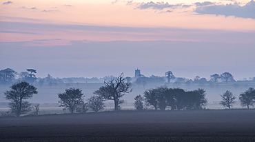 A view across fields on a misty morning towards the village of Martham, Norfolk, England, United Kingdom, Europe