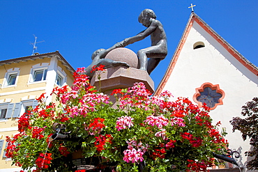 Statues and geraniums in Town Square, Ortisei, Gardena Valley, Bolzano Province, Trentino-Alto Adige/South Tyrol, Italian Dolomites, Italy, Europe