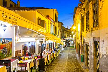 View of cafes in cobbled street in old town at dusk, Funchal, Madeira, Portugal, Europe