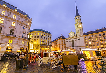 Christmas Market stalls and St. Michael Catholic Church in Michaelerplatz, Vienna, Austria, Europe