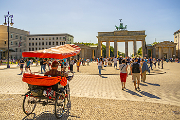 View of Brandenburg Gate, rickshaw and visitors in Pariser Platz on sunny day, Mitte, Berlin, Germany, Europe