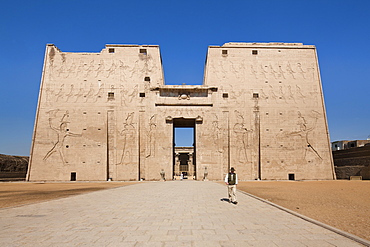 Man standing by the entrance pylon of the Temple of Horus, Edfu, Egypt, North Africa, Africa